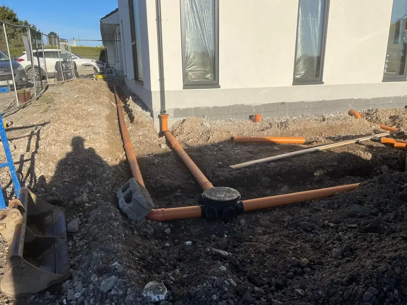 Drainage inspection chamber installed and connected to underground pipework beside a new build