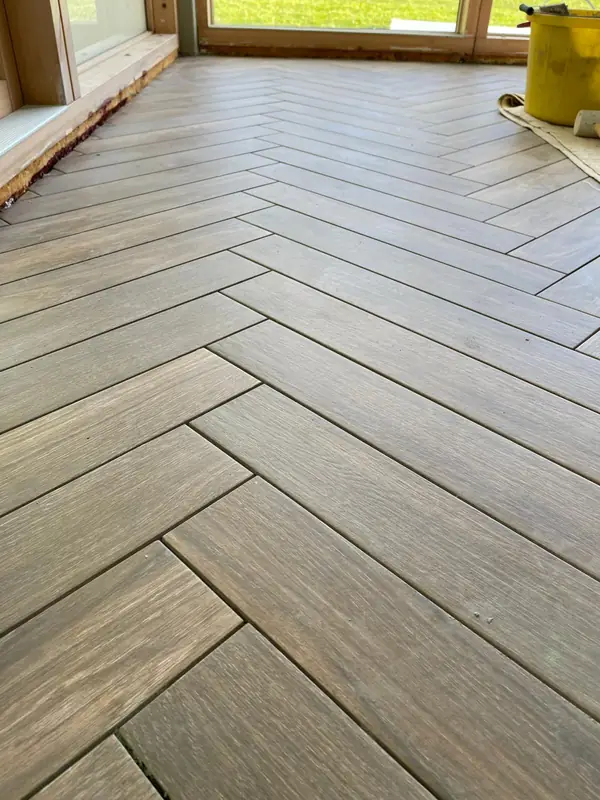 Close detail of wood-effect porcelain tiles laid in a herringbone pattern with tight joints