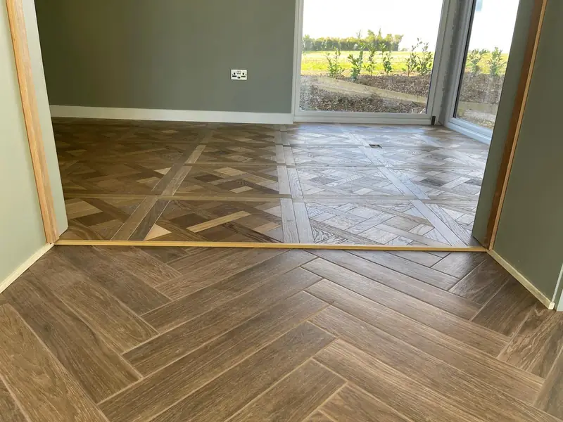 Living room with a decorative parquet-pattern tiled floor meeting a herringbone laid hallway