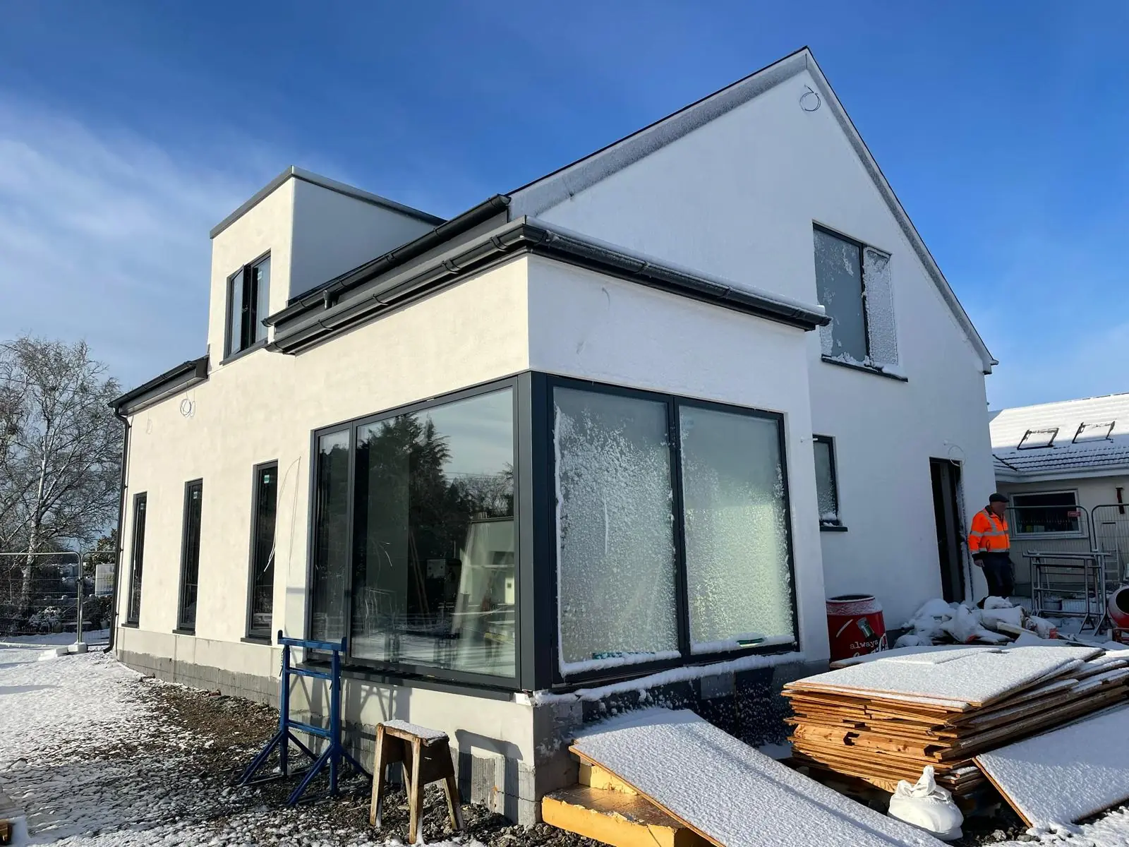New build house with white render and large glazing, photographed during construction