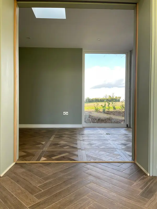 Finished room with parquet-pattern floor tiling, sage green walls and a full-height picture window
